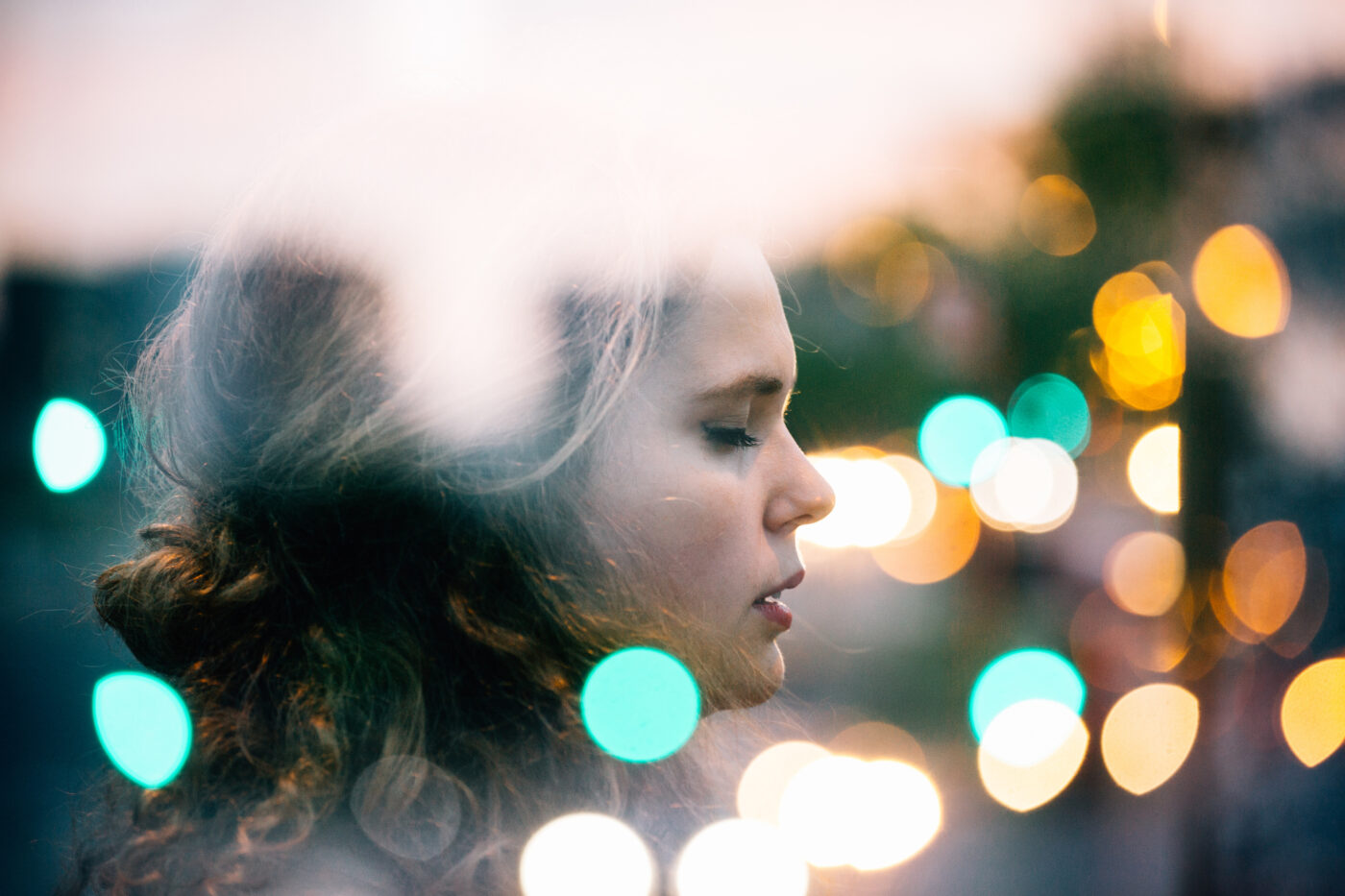 Double exposure of young woman with bokeh city lights.